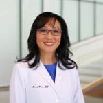 Dr. Won standing in front of office in white doctor's jacket.