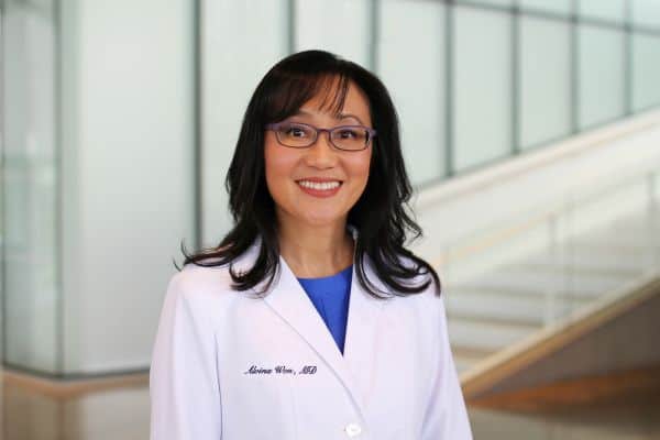 Dr. Won standing in front of office in white doctor's jacket.