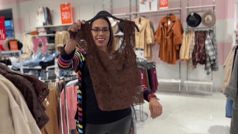 Jennifer, an ESG patient, smiles while shopping—holding up a stylish lace top that symbolizes her confidence and joy after her weight loss journey.